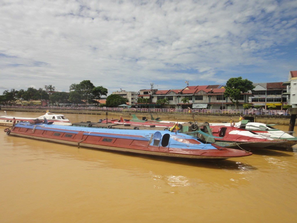Express boats on the Batang Rejang, Sarawak, Borneo, Malaysia. Long, low, closed steel express boats waiting in port on the golden waters of the Batang Rejang, Sarawak, Borneo, Malaysia.