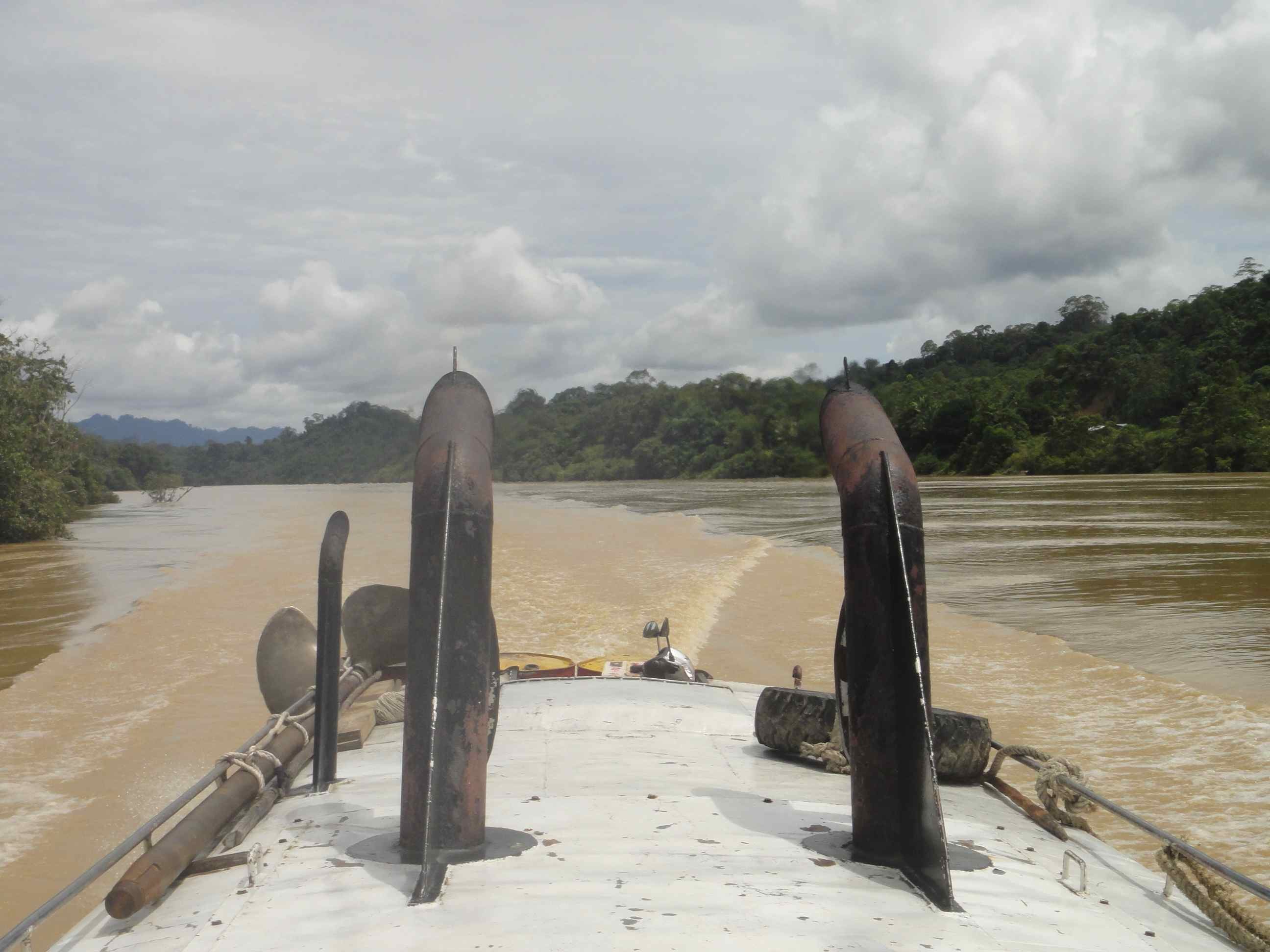 From the roof of an express boat on the Batang Rejang, Sarawak, Borneo, Malaysia. Looking back from the roof of an express boat over its wake on the Batang Rejang, Sarawak, Borneo, Malaysia, with exhaust pipes in the foreground.