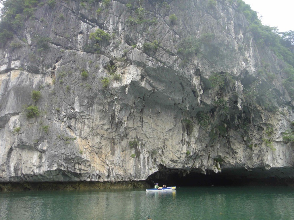 kayaking_halong_bay_vietnam Kayak approaching gap in base of limestone cliff: Halong Bay, Vietnam.