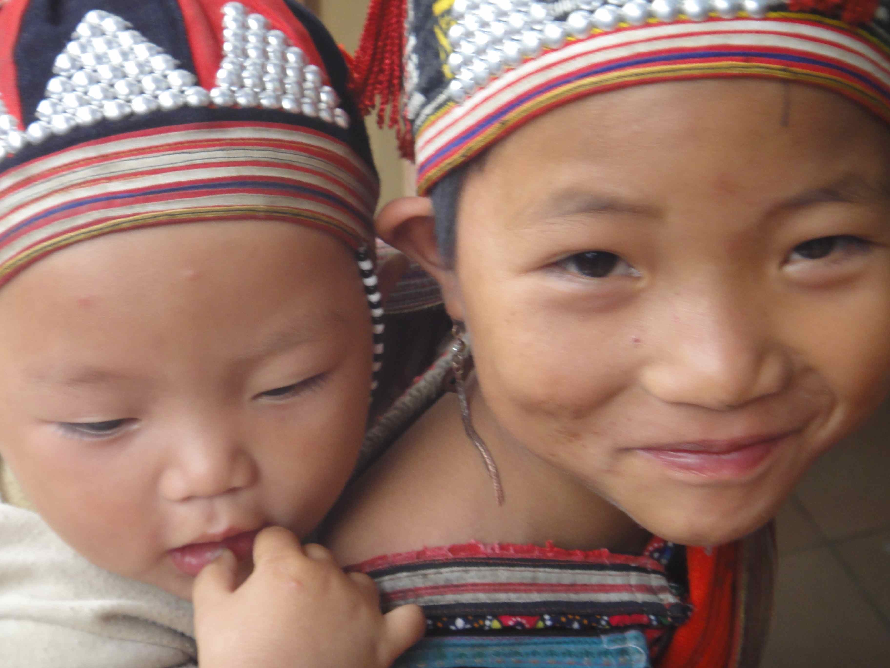 smiling_hmong_sister Hmong girl with her brother on back, smiling for the camera, Sapa, Vietnam.