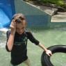 Z, grinning, coming off slide with rubber ring. Poring Hot Springs, Kinabalu Park, Sabah, Borneo, Malaysia.