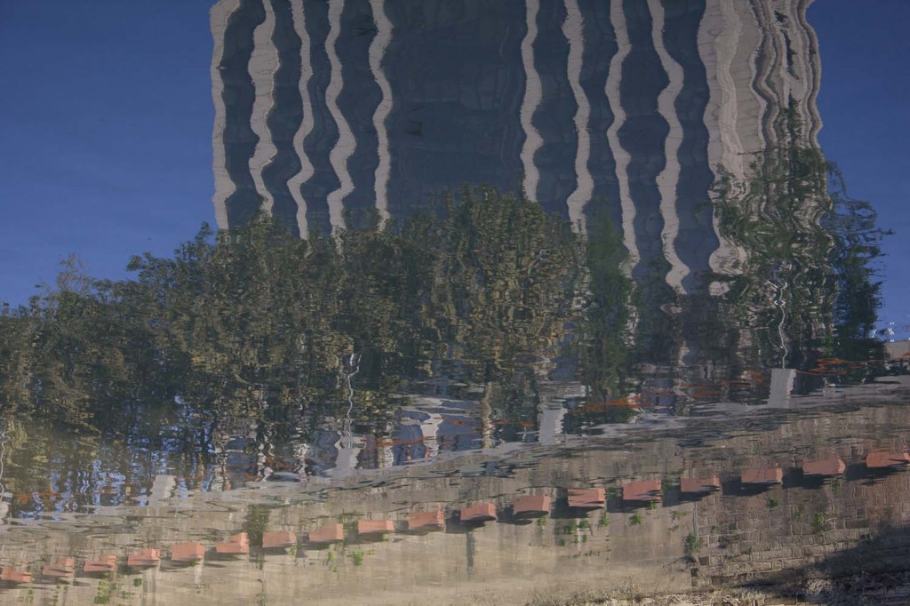 Tower block, trees and embankment reflected in the Jin River, Chengdu, China.