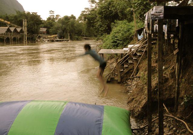 Fluid Bar Vang Vieng jumping onto a green and blue inflatable at Fluid Bar, Vang Vieng