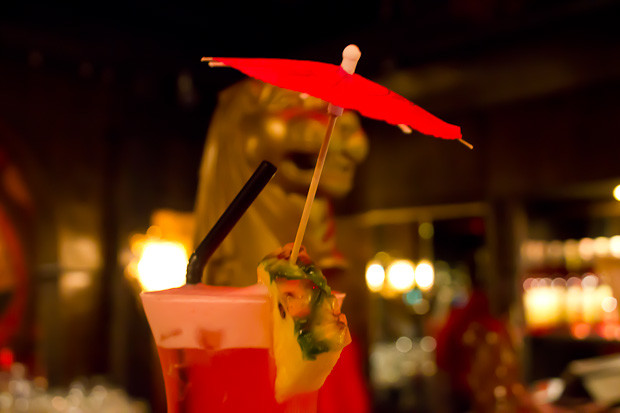 Singapore Sling by Night Singapore Sling with pink umbrella, gold Chinese lion in the background.