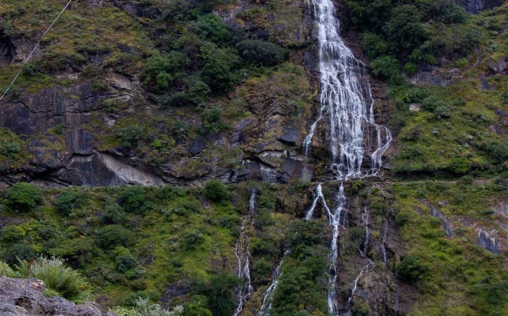 Waterfall running across narrow, cliffside path in Tiger Leaping Gorge, China.