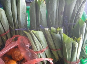 Tall, folded, fresh green betel leaves and orangey areca fruits on display in Belaga, Sarawak, Borneo, Malaysia.