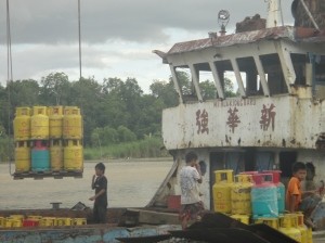Canisters of cooking gas being loaded onto a boat. Secured with plastic packing tape. Marudi, Sarawak, Borneo, Malaysia.