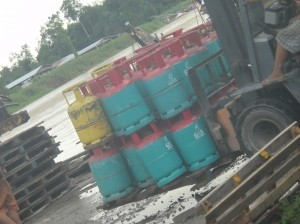 Gas canisters secured with packing tape swing onto a boat. Marudi, Sarawak, Borneo, Malaysia.