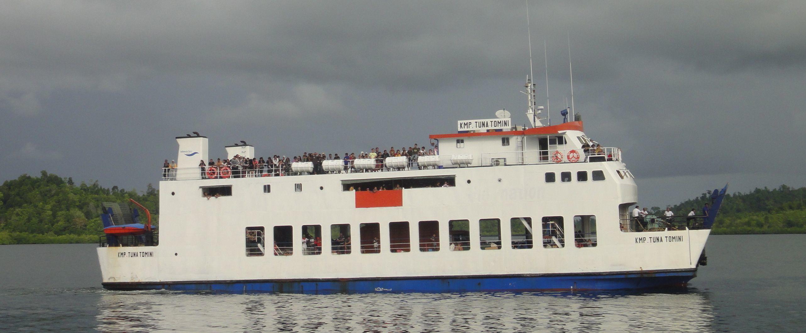 ferry crowded with people on deck ferry pulls into wakai, togian islands, sulawesi, indonesia.