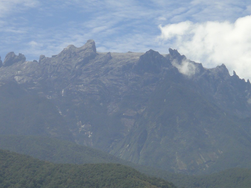 Mount Kinabulu The spiky, lunar peaks of Mount Kinabulu framed by sky and tea plantations. Sabah, Borneo, Malaysia.