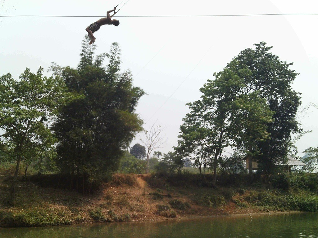 Rope-Swing-Nam-Song-River-Vang-Vieng-Laos Soaring on a rope swing high above the Nam Song river in Vang, Vieng, Laos