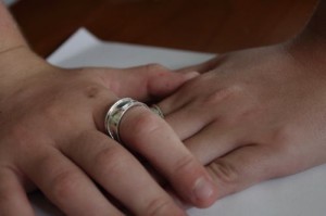 boys hands clasping each other wearing silver rings.
