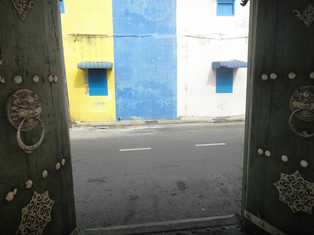 the doors of wisdom coloured shophouse fronts between ornate doors in georgetown, penang, malaysia.