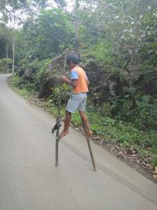 Torajan boy racing along the street on bamboo stilts. Tana Toraja, Sulawesi, Indonesia.