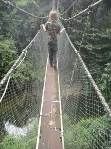 Z making his way along an aerial suspension bridge at canopy level, over a jungle river. Mulu National Park, Sarawak, Borneo, Malaysia.