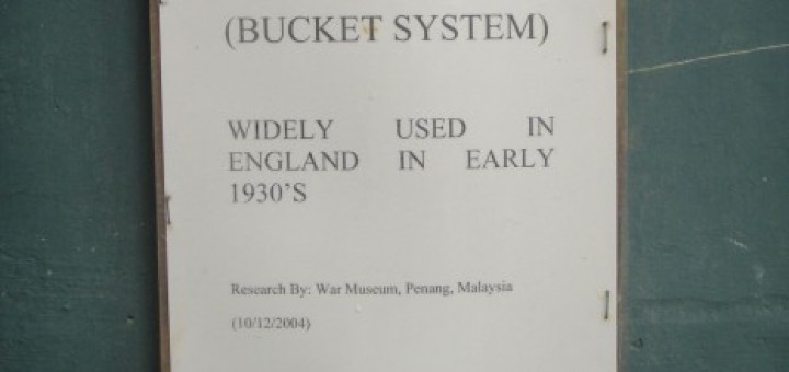 Sign on wall reading: "Toilet (Bucket system). Widely used in England in the 1930s."