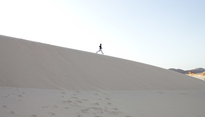 Zac running down a sand dune.