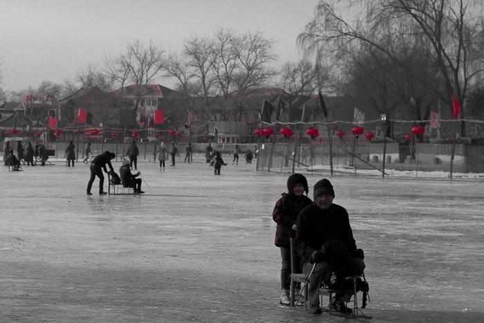Ice skating in Beijing: little girl pushing her grandfather along.