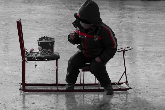 Ice skating in Beijing: child eats popcorn off a skating chair.