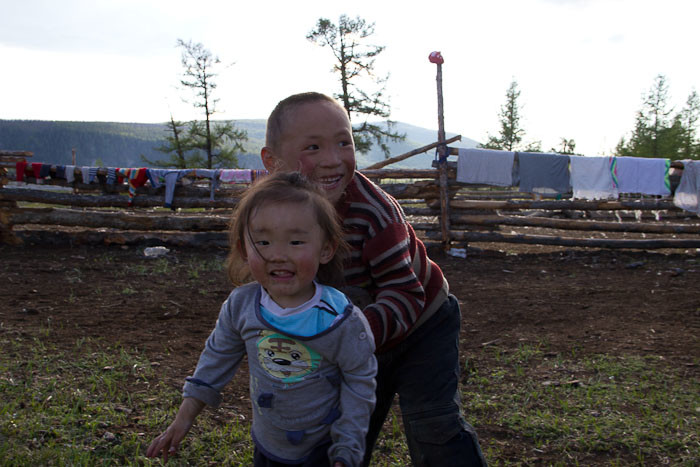Kids playing against a backdrop of laundry, outside a Mongolian ger.