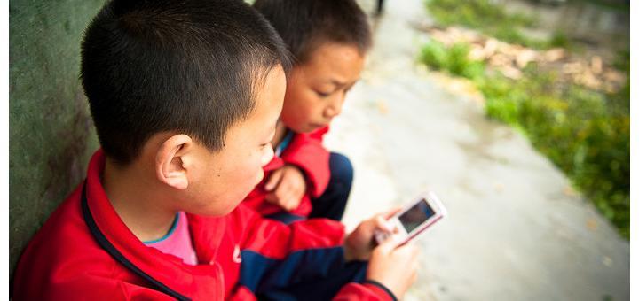 Primary school children in Liu Lin, Hubei, China, playing with a mobile phone.
