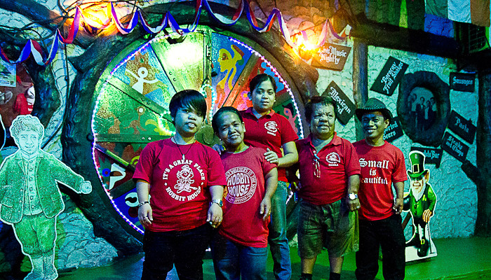 Staff at Hobbit House, Manila, beside the Burrow door.