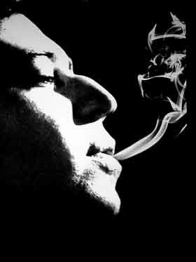 Serge Gainsbourg exhaling cigarette smoke.