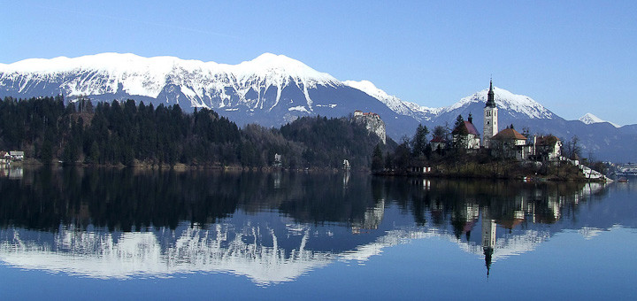 Lake Bled, Slovenia, with snow-capped mountains reflected in its waters.