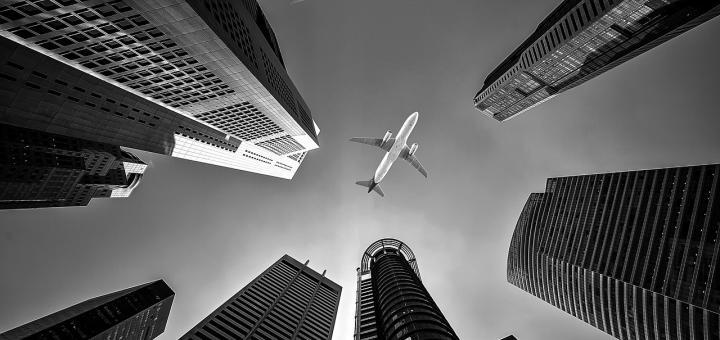 Aircraft between skyscrapers in black and white.
