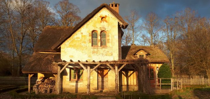 Light shines on a rustic building in Marie-Antoinette's Hameau at Versailles