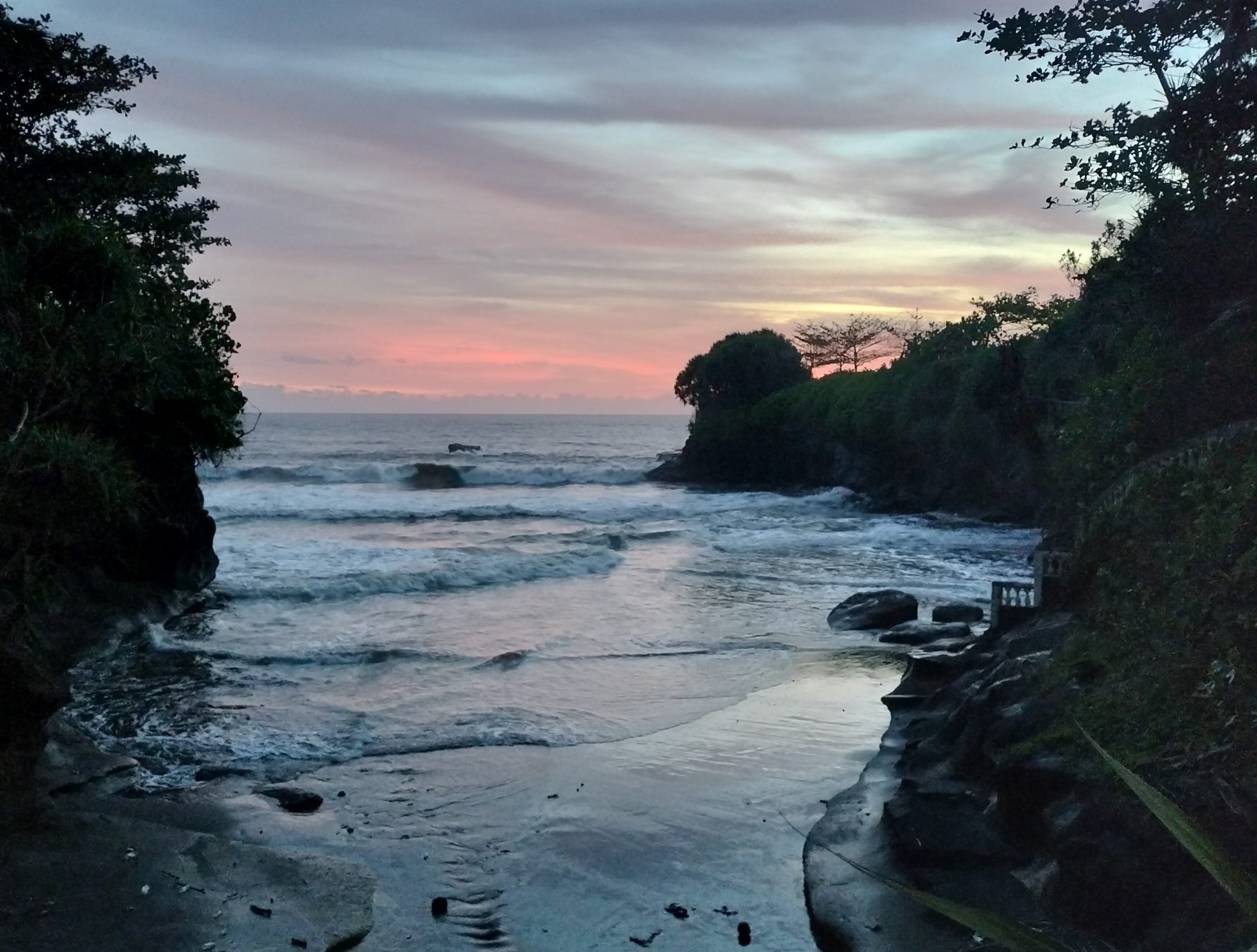 Sunset over a rocky cove in Balian, Bali.